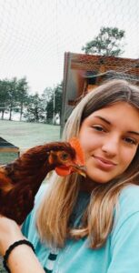 Teenager holding a pet chicken at the chicken coop