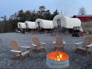 Four covered wagons with fire in a firepit in the foreground
